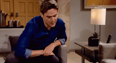 A Man In A Blue Shirt Is Sitting On A Couch In Front Of A Lamp That Says Global GIF