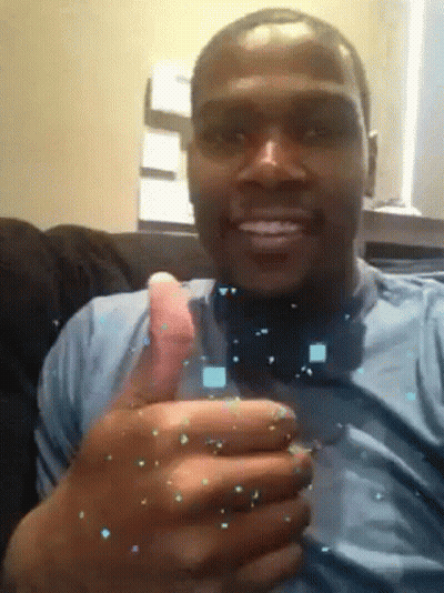 A Man In A Blue Shirt Is Smiling And Holding A Glass In His Hand GIF
