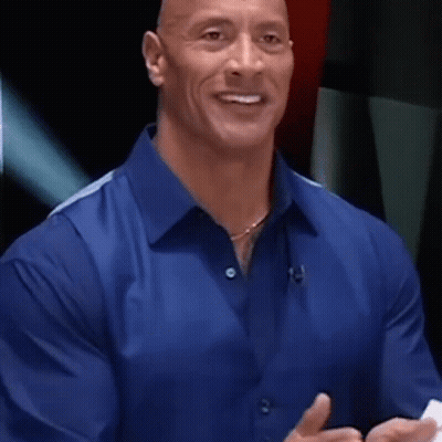 A Man In A Blue Shirt Is Smiling And Talking While Holding A Piece Of Paper . GIF