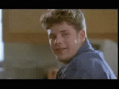 A Man In A Blue Shirt Is Smiling In A Blurry Photo . GIF