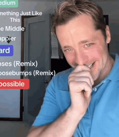 A Man In A Blue Shirt Is Smiling In Front Of A Sign That Says " Medium " GIF
