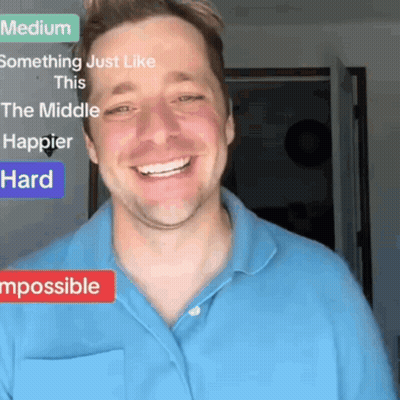 A Man In A Blue Shirt Is Smiling In Front Of A Sign That Says Something Just Like This GIF
