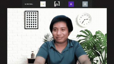 A Man In A Blue Shirt Is Smiling In Front Of A Wall With A Clock That Says 10:08 GIF