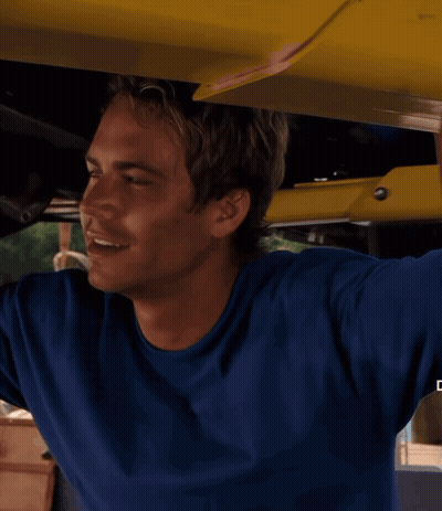 A Man In A Blue Shirt Is Smiling While Holding A Yellow Object GIF
