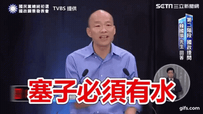 A Man In A Blue Shirt Is Speaking Into A Microphone With Chinese Writing On It GIF