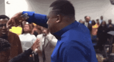 A Man In A Blue Shirt Is Standing In A Crowd GIF