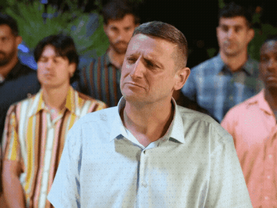A Man In A Blue Shirt Is Standing In A Crowd Of Men GIF