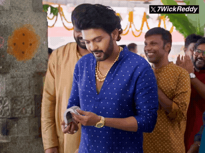 A Man In A Blue Shirt Is Standing In A Crowd With A 7Wick Reddy Logo In The Corner GIF