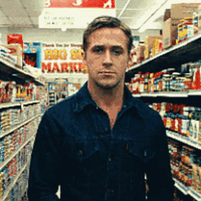 A Man In A Blue Shirt Is Standing In A Grocery Store With A Sign That Says Big Sale Market GIF