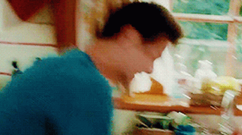 A Man In A Blue Shirt Is Standing In A Kitchen GIF