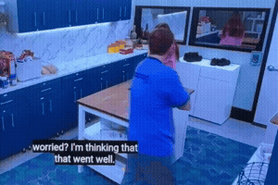 A Man In A Blue Shirt Is Standing In A Kitchen Talking To Another Man GIF