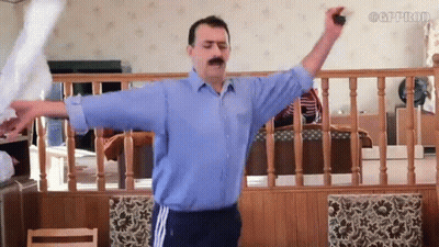 A Man In A Blue Shirt Is Standing In A Living Room With His Arms Outstretched .. GIF