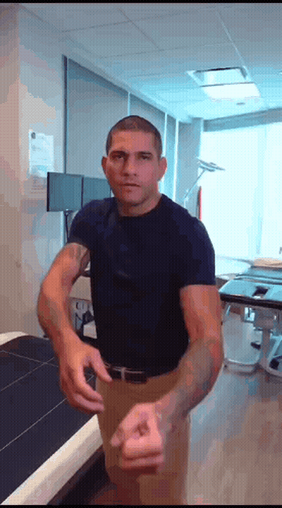 A Man In A Blue Shirt Is Standing In A Room With His Arms Outstretched GIF