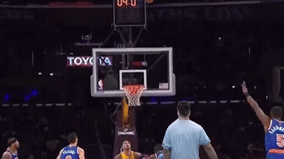 A Man In A Blue Shirt Is Standing In Front Of A Basketball Hoop With A Toyota Ad In The Background GIF