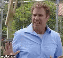 A Man In A Blue Shirt Is Standing In Front Of A Chain Link Fence Making A Funny Face . GIF