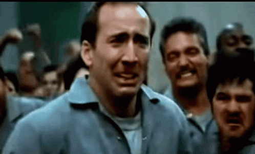 A Man In A Blue Shirt Is Standing In Front Of A Crowd Of Men . GIF