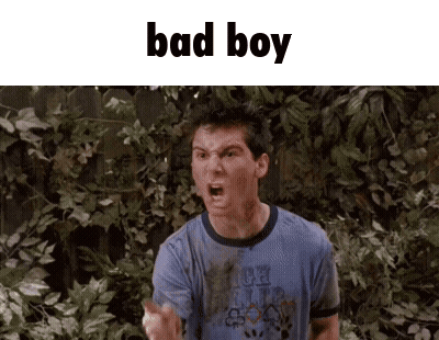 A Man In A Blue Shirt Is Standing In Front Of A Fence And Making A Funny Face . GIF