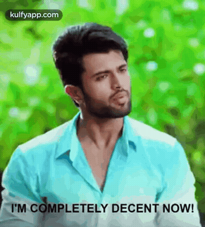 A Man In A Blue Shirt Is Standing In Front Of A Green Background And Says `` I 'M Completely Decent Now ! '' GIF
