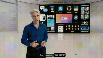 A Man In A Blue Shirt Is Standing In Front Of A Large Screen That Says Ios On It . GIF