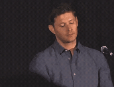 A Man In A Blue Shirt Is Standing In Front Of A Microphone With His Eyes Closed GIF