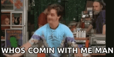 A Man In A Blue Shirt Is Standing In Front Of A Record Store . GIF
