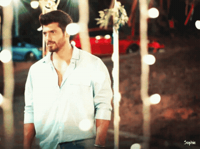 A Man In A Blue Shirt Is Standing In Front Of A Red Car And Trees GIF