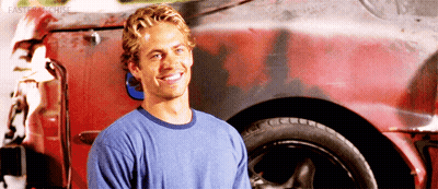 A Man In A Blue Shirt Is Standing In Front Of A Red Car GIF