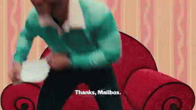 A Man In A Blue Shirt Is Standing In Front Of A Red Couch Holding A Plate . GIF