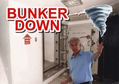 A Man In A Blue Shirt Is Standing In Front Of A Sign That Says " Bunker Down " GIF