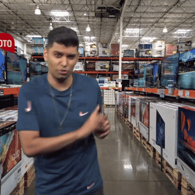 A Man In A Blue Shirt Is Standing In Front Of A Sign That Says Oto GIF