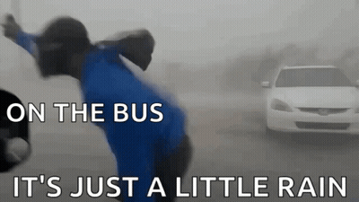 A Man In A Blue Shirt Is Standing In Front Of A White Car With The Words On The Bus It 'S Just A Little Rain GIF