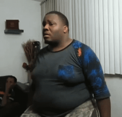 A Man In A Blue Shirt Is Standing In Front Of A White Curtain . GIF