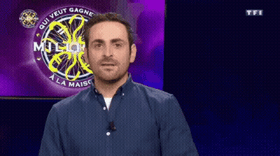 A Man In A Blue Shirt Is Standing In Front Of A Who Wants To Be A Millionaire Sign GIF