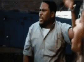 A Man In A Blue Shirt Is Standing In Front Of A Woman . GIF