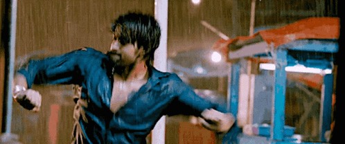 A Man In A Blue Shirt Is Standing In The Rain With His Arms Outstretched GIF