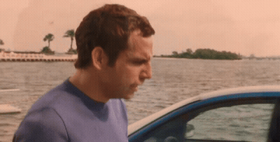 A Man In A Blue Shirt Is Standing Next To A Car Near The Water GIF