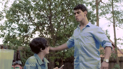 A Man In A Blue Shirt Is Standing Next To A Woman In A Blue Shirt GIF