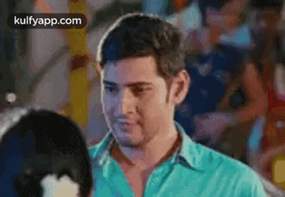 A Man In A Blue Shirt Is Standing Next To A Woman In A Crowded Room . GIF