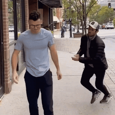 A Man In A Blue Shirt Is Standing Next To Another Man GIF