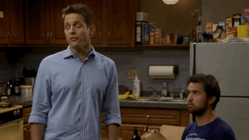 A Man In A Blue Shirt Is Standing Next To Another Man GIF