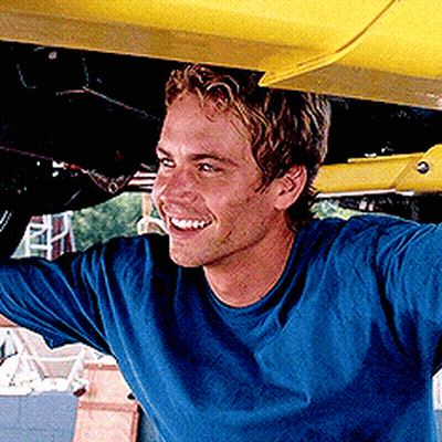A Man In A Blue Shirt Is Standing Under A Yellow Car GIF