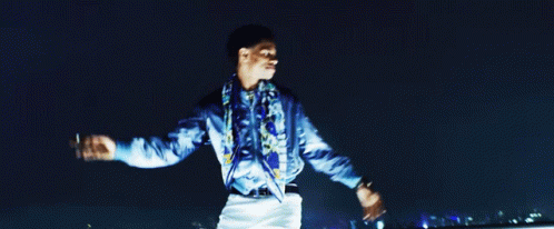 A Man In A Blue Shirt Is Standing With His Arms Outstretched GIF
