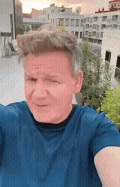 A Man In A Blue Shirt Is Taking A Selfie On A Rooftop With A City In The Background . GIF