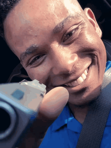 A Man In A Blue Shirt Is Taking A Selfie With A Camera GIF
