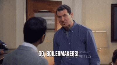 A Man In A Blue Shirt Is Talking To Another Man And Says Go Boilermakers GIF