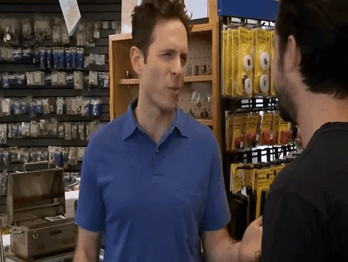 A Man In A Blue Shirt Is Talking To Another Man GIF