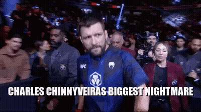 A Man In A Blue Shirt Is Walking Out Of A Boxing Ring . GIF