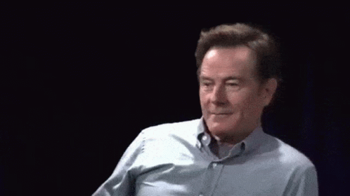 A Man In A Blue Shirt Is Waving At The Camera GIF