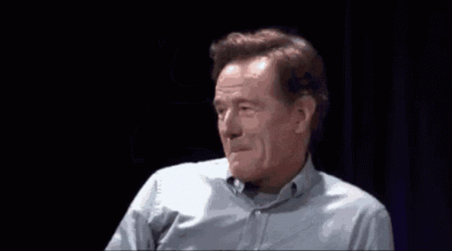 A Man In A Blue Shirt Is Waving His Hand In Front Of His Face GIF