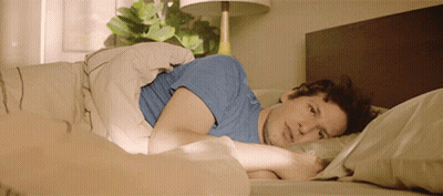 A Man In A Blue Shirt Laying In Bed GIF